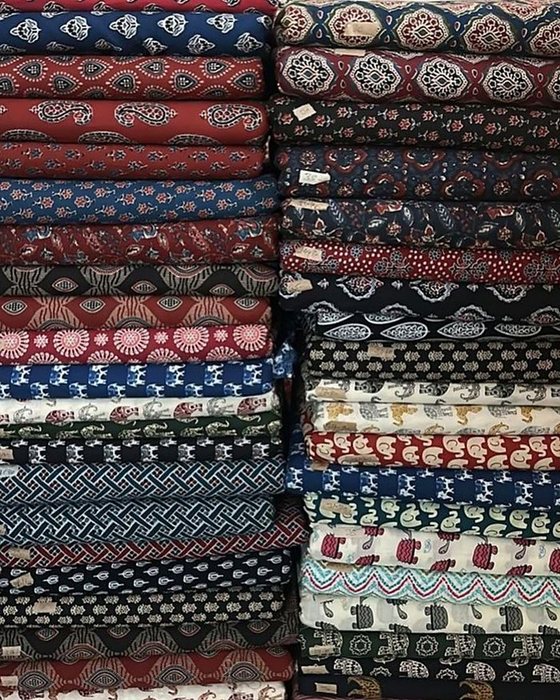 Stacks of printed cotton material folded on the shelves