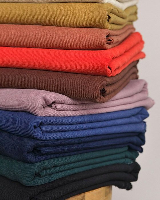 A stack of plain cotton fabrics in many colours