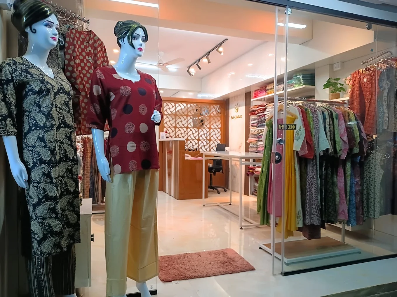 Sri Chakra shopfront: mannequins in printed cotton kurtis and racks of kurtis behind the glass door